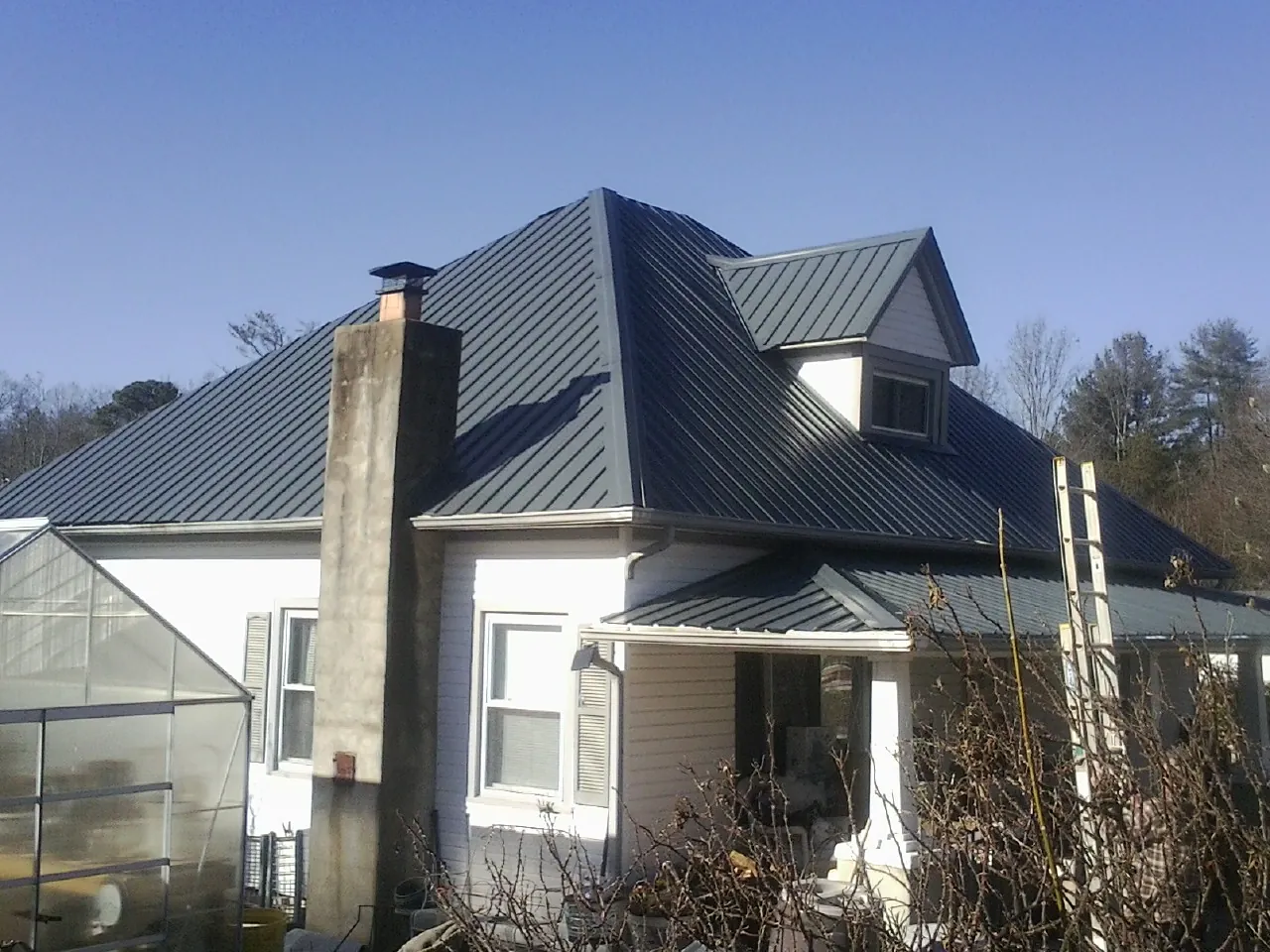 Dark blue standing seam metal roof on a white farmhouse with dormer — Slate & Tile Roof Repair by Roofing Brothers in Otley