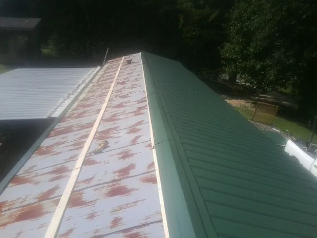 Old rusted panels beside newly installed green metal roofing — Wind Damage Roof Repair by Roofing Brothers in Otley