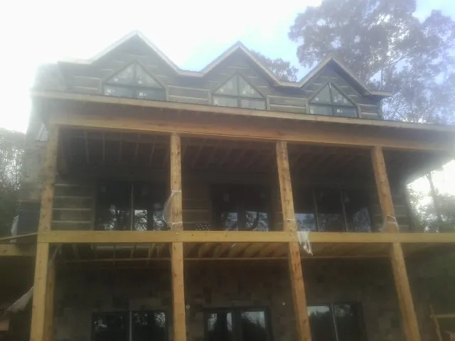 Dormers and porch framing on a large log home under construction — Roof Coating work by our crew in Otley