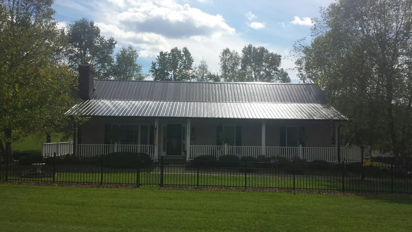 Gray metal roof on a brick ranch with a full width front porch — Gutter Guard Installation work by our crew in Otley