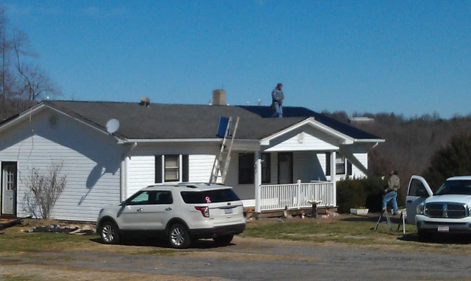 Roofers stripping shingles from a white ranch house roof in Otley
