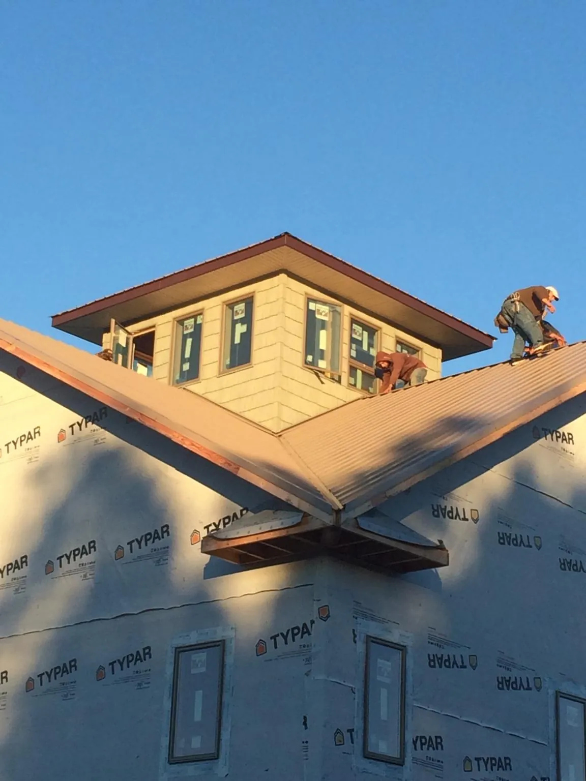 Roofers working around a rooftop cupola on a new metal roof at sunset — Roof Waterproofing in Otley by Roofing Brothers